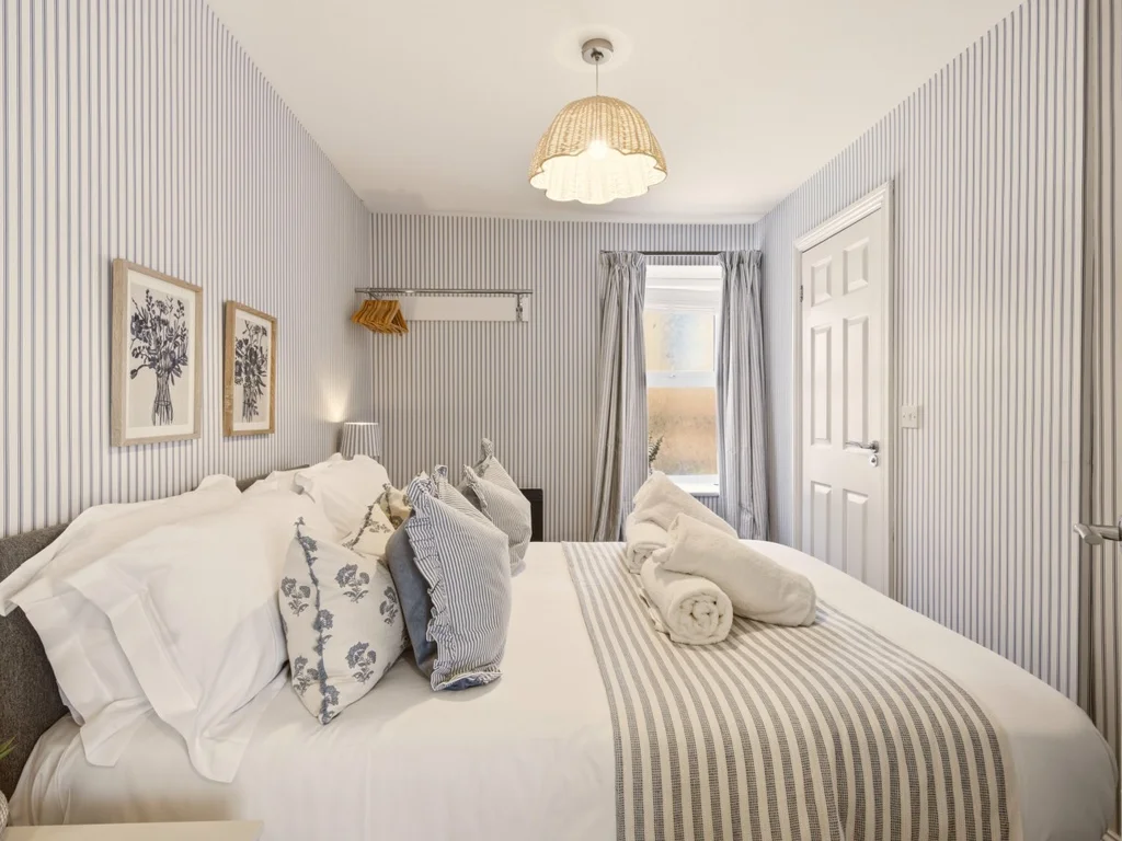 Double bedroom with striped décor, feature lighting and bedside tables.