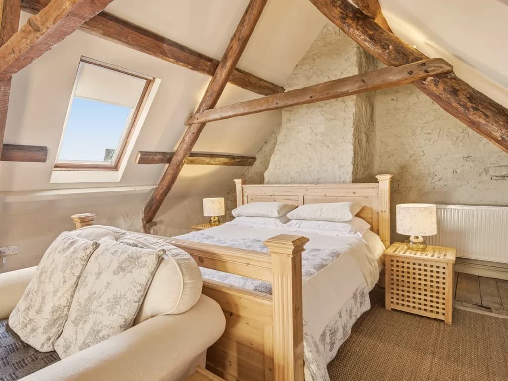 Super king bedroom with exposed beams and a cosy seating area
