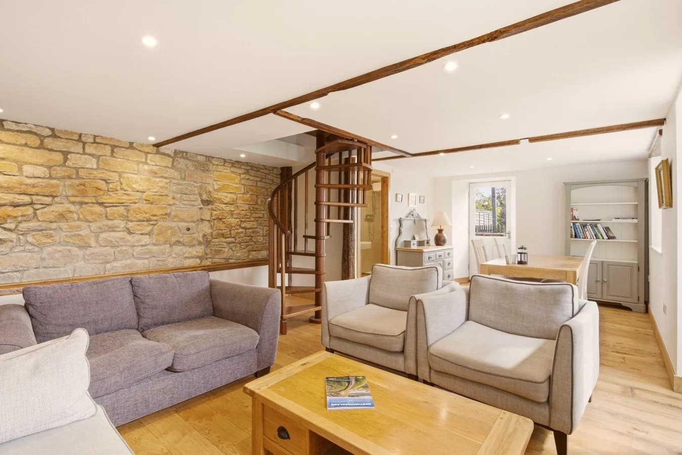 Living area with exposed stone wall and spiral staircase