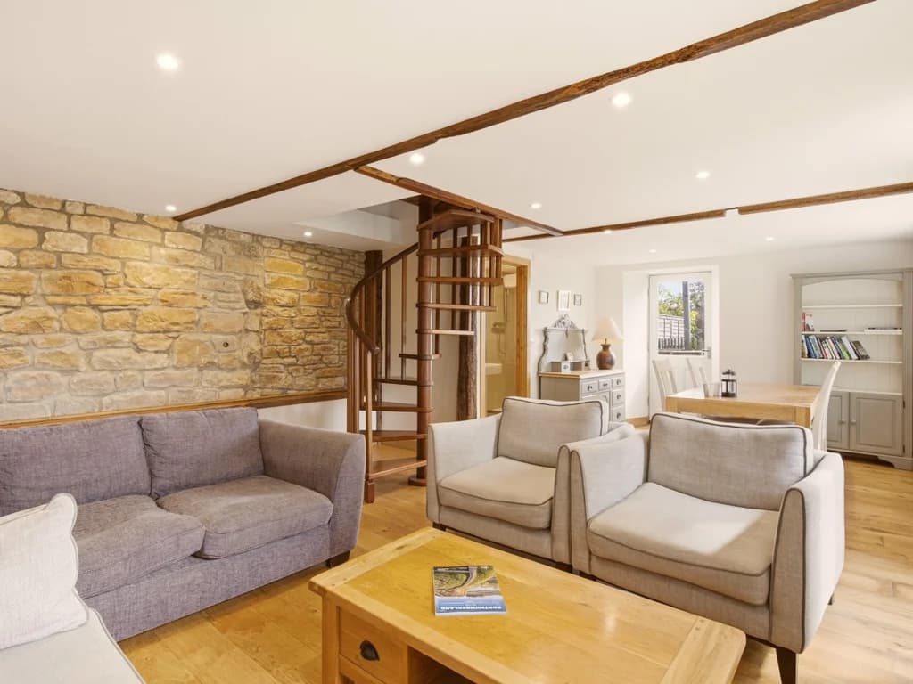 Living area with exposed stone wall and spiral staircase