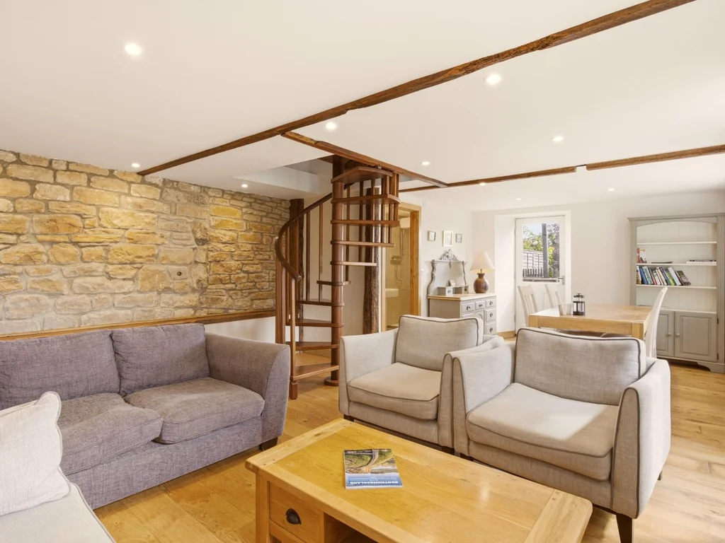 Living area with exposed stone wall and spiral staircase