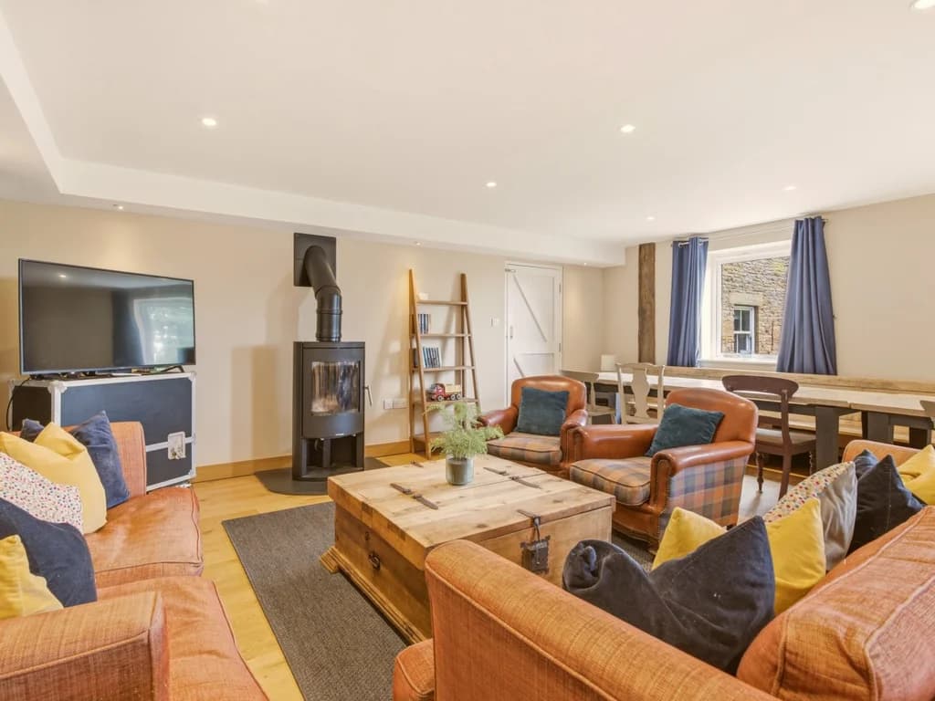 Spacious living area with sofas, TV and wood-burning stove