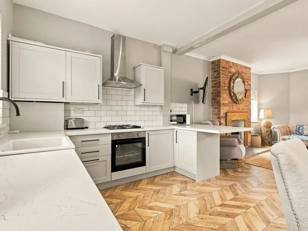 Open-plan kitchen with breakfast bar and herringbone wood flooring.
