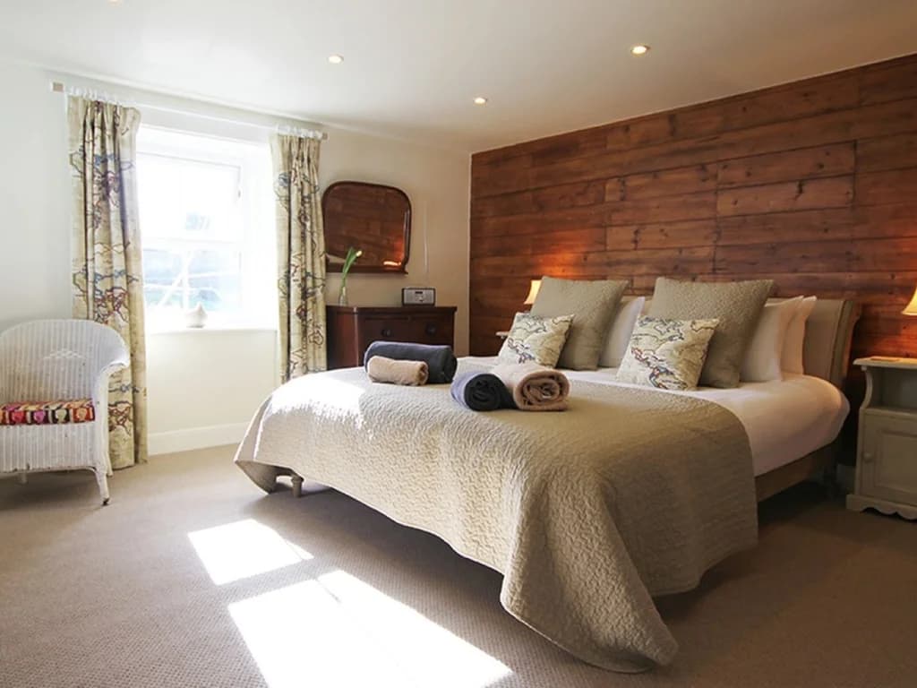 Spacious super king bedroom with warm wood feature wall.