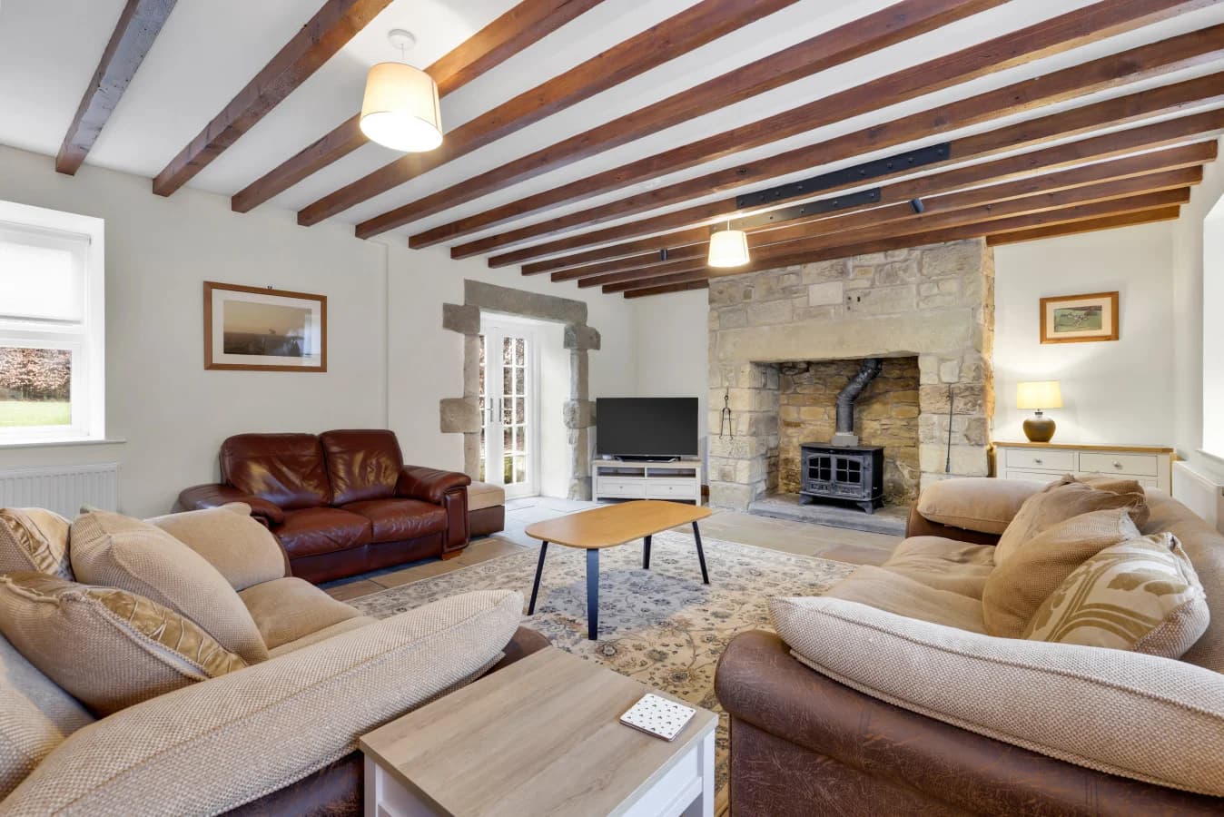 Spacious farmhouse lounge with exposed beams and stone fireplace